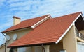 Modern house with chimney, red clay tiled roof and gable and valley type of roof construction. Building attic house construction Royalty Free Stock Photo