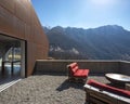 Modern house exteriors with veranda. Red sofa overlooking the mountains of Switzerland Royalty Free Stock Photo