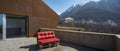 Modern house exteriors with veranda. Red sofa overlooking the mountains of Switzerland Royalty Free Stock Photo