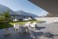 Modern house with garden. In the foreground is a small living room with armchairs and small tables; at the back is the pool with a Royalty Free Stock Photo