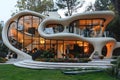 A modern house with a unique curved futuristic architecture. Housing in the forest.