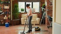 Modern housewife sweeping dust with mop in apartment