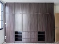 Modern huge brown wooden wardrobe in the white room, closed, front view. Royalty Free Stock Photo