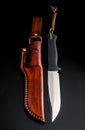 A modern hunting knife and a leather case for him on a dark background. Melee weapons for hunting and self-defense. The instrument