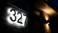 Illuminated House Numbers 327 on Brick Wall at Night with Exterior Lighting Royalty Free Stock Photo