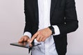 Modern image of tablet in hands of young businessman in white shirt, black jacket on white background. Being busy