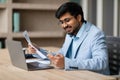 Modern Indian professional businessman immersed in paperwork at office,