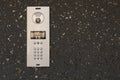 Modern intercom system with numeric keypad, speaker, and camera installed on dark textured stone wall Royalty Free Stock Photo
