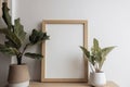 Mockup picture frame and houseplants on a wooden table create a natural and organic vibe