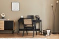 Modern interior design of home office space with stylish chair, desk, commode, black mock up poster frame, laptop, book, office.