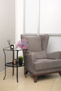 Modern Interior detais, an armchair next to metallic tea table with candles and aromadiffuser. cozy home. copy space for