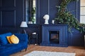 Modern interior with fireplace, spacious living room with dark blue walls and wooden floor.