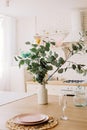 Modern interior of a white light kitchen in a Scandinavian style, a wooden table, linen textiles, a cart with eucalyptus are Royalty Free Stock Photo