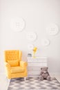 Modern interior with white and yellow colors. Yellow soft armchair ear white bedside. Comfort chair. Armchair with