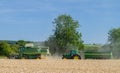 Modern John Deere combine harvester cutting crops with tractor and trailer Royalty Free Stock Photo