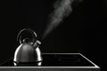 Modern kettle with whistle on stove against black background Royalty Free Stock Photo