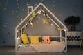 Modern kids bedroom in the evening. House bed decorated with lights garland