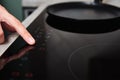 Woman hand turns on modern induction stove in the kitchen Royalty Free Stock Photo