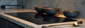 Modern kitchen countertop with induction cooktop and elegant black ceramic bowls Royalty Free Stock Photo