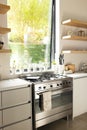 A modern kitchen features a stainless steel stove and white countertops with copy space Royalty Free Stock Photo