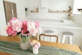 Modern kitchen interior. Beautiful peonies in vase on wooden table on background of stylish white kitchen with appliances in new Royalty Free Stock Photo