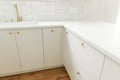 Modern kitchen interior. Stylish white kitchen cabinets with brass faucet and knobs, granite island and appliances in new Royalty Free Stock Photo