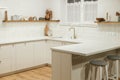 Modern kitchen interior. Stylish white kitchen cabinets with brass knobs, granite island, appliances and evening light in new Royalty Free Stock Photo
