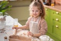 At modern kitchen island charismatic little girl blowing the flour in front of the camera while preparing some delicious