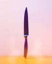 Modern kitchen knife standing on a yellow surface, illuminated by colored lights Royalty Free Stock Photo