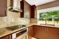 Modern kitchen room with matte brown cabinets and granite trim.