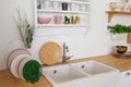 Modern kitchen with sink and utensils near light wall. Plates and caps, wooden surface of the table Royalty Free Stock Photo