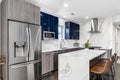 A modern kitchen with white counter tops and blue and wood two tone cabinets.