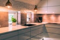 Modern kitchenette with white worktop, black sink and coppery metal lamps