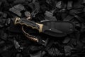 Modern knife with black blade. Hunting, military knife on smoldering charcoal. Black back