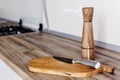 Modern knife on wooden cutting board with pepper spice on wooden table top. Cooking on modern kitchen with furniture in grey color