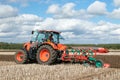 Modern Kubota tractor pulling a plough