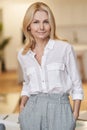 Modern lady. Smart mature business woman with blonde hair looking at camera while standing indoors