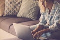 Modern lady working online with laptop computer comfortably sitting on the sofa at home. Concept of smart working lifestyle female