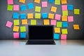 Modern laptop and blank colorful sticky notes on wall background