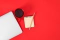 Modern laptop with cup of coffee and office tools on red background. Space for text Royalty Free Stock Photo
