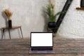 Modern laptop with empty screen on the wooden table with contemporary flat at the background. Mockup, copy space Royalty Free Stock Photo