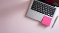 Modern laptop keyboard with pink sticky note and silver pen on pastel pink workspace surface Royalty Free Stock Photo
