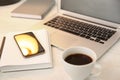 Modern laptop, smartphone, cup of coffee and notebook on white table, closeup Royalty Free Stock Photo