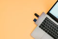 Modern laptop with USB Type-C adapter and flash drives is isolated on an orange background Royalty Free Stock Photo