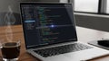 Modern laptop on wooden desk displaying code with coffee nearby Royalty Free Stock Photo