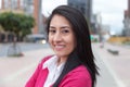 Modern latin woman with a pink vest outside in the city