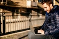 Modern lifestyle - young man wearing jacket working from outdoor offic