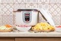 Modern, light multi cooker and products on table in kitchen. Cooking stewed potatoes with meat in multicooker Royalty Free Stock Photo