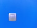 Modern light switch on a vibrant blue wall providing a striking contrast Royalty Free Stock Photo