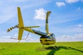 Modern small light helicopter on a grassy field against the blue sky Royalty Free Stock Photo